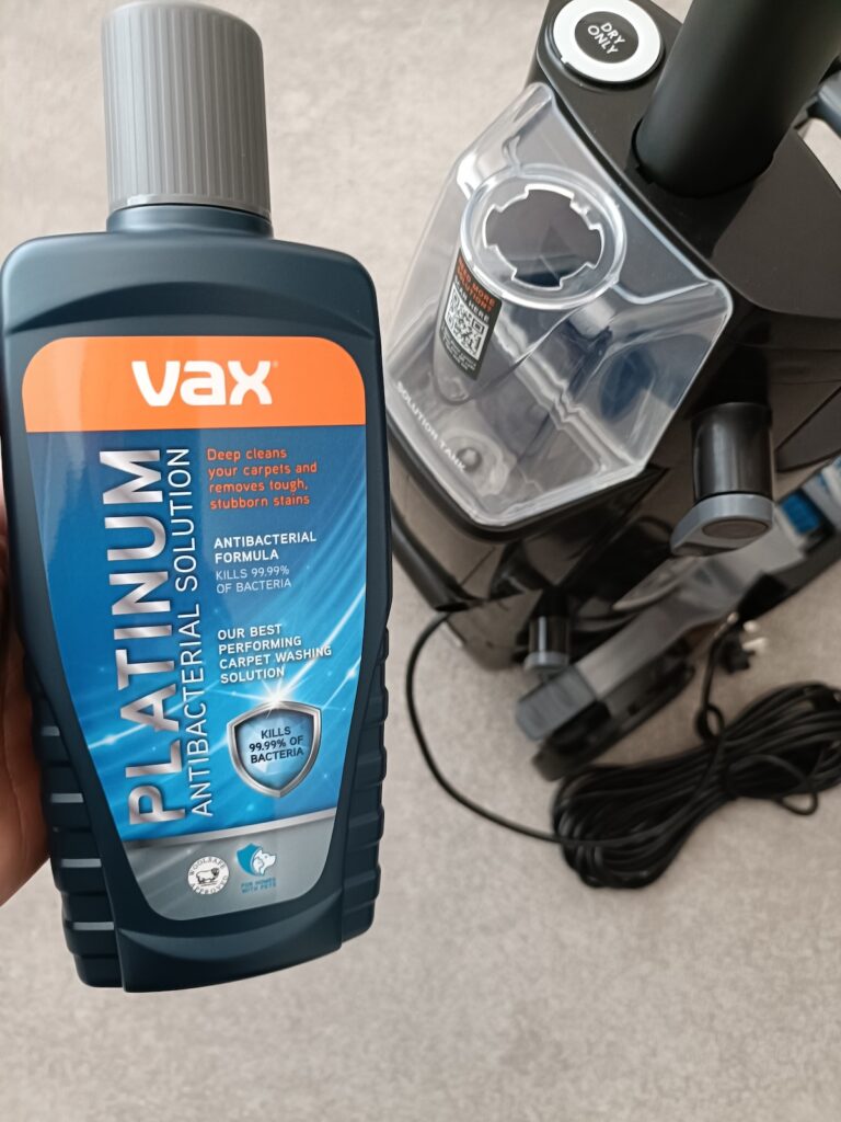 Platinum Cleaning Solution bottle held alongside the cleaning solution tank