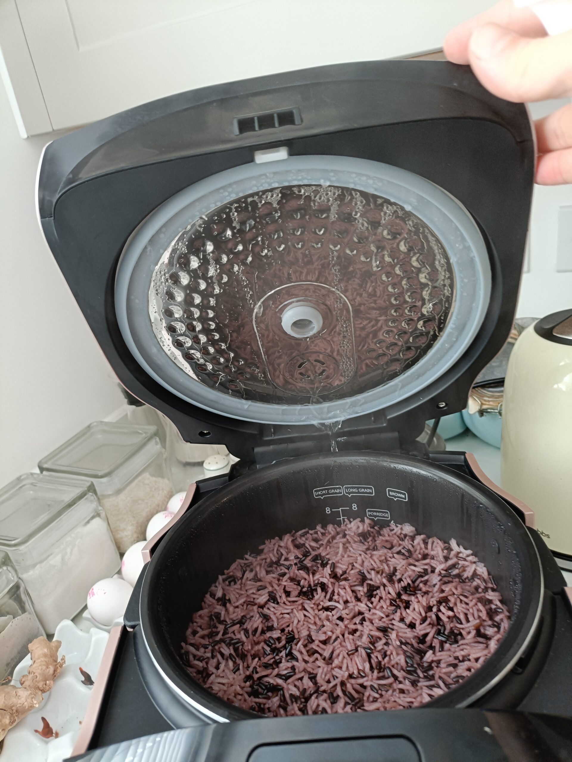 Opening the lid of the rice cooker with cooked rice inside